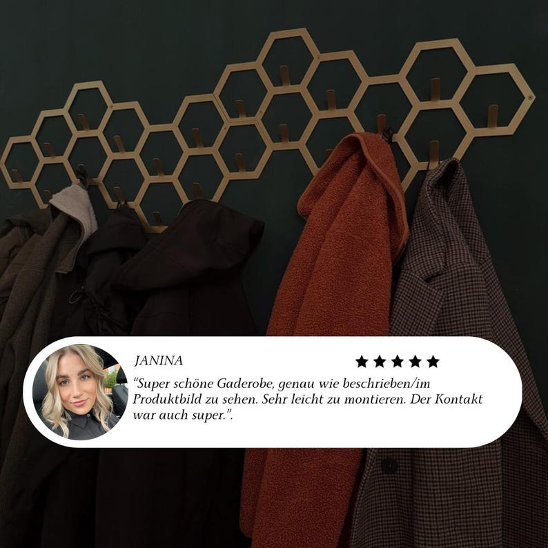 May include: A gold-colored, honeycomb-shaped wall-mounted coat rack with wooden pegs, holding various coats and jackets. The rack is mounted on a dark green wall. A customer review is visible in the image.