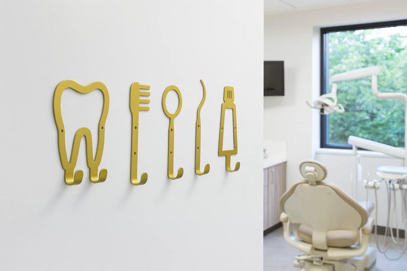 Peut inclure: Un ensemble de cinq pat&egrave;res murales en m&eacute;tal dor&eacute; en forme d'instruments dentaires, comprenant une dent, une brosse &agrave; dents, un miroir dentaire, une sonde et un tube de dentifrice, chacune avec deux petits trous de vis pour la fixation murale.