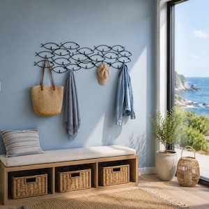 Könnte beinhalten: Eine schwarze Wandgarderobe aus Metall mit einem Fischschwarm-Design und mehreren Haken. Die Garderobe hält eine beige geflochtene Tasche, einen grauen Schal, eine beige Baseballkappe und eine hellblaue Jeansjacke über einer Holzbank mit drei geflochtenen Körben.