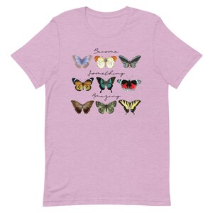 May include: A light pink t-shirt with a graphic of colorful butterflies and the text "Become something amazing".