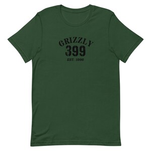 May include: A green short-sleeved t-shirt with a black graphic print that says "Grizzly 399 Est. 1996".