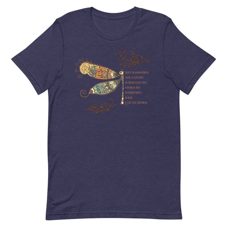 May include: Navy blue t-shirt with a dragonfly graphic and the text "They whispered you cannot withstand the storm, she whispered back I am the storm".