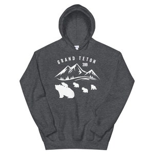 May include: A dark grey hooded sweatshirt with a white graphic design of a mountain range with the text "GRAND TETON 399" and a mother bear with cubs.