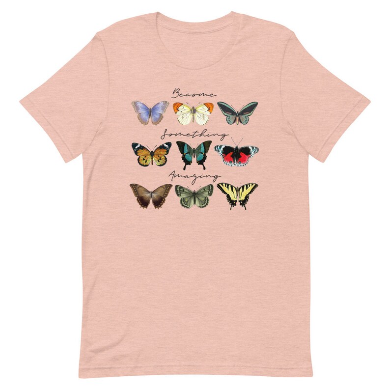 May include: A light pink t-shirt with a graphic of colorful butterflies and the text "Become something amazing".