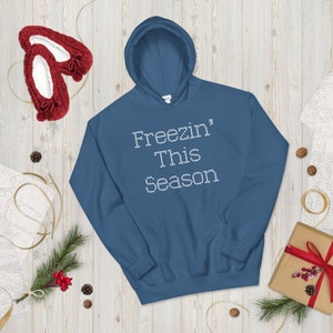 May include: A dark blue hooded sweatshirt with the text "Freezin' This Season" in white rhinestones.