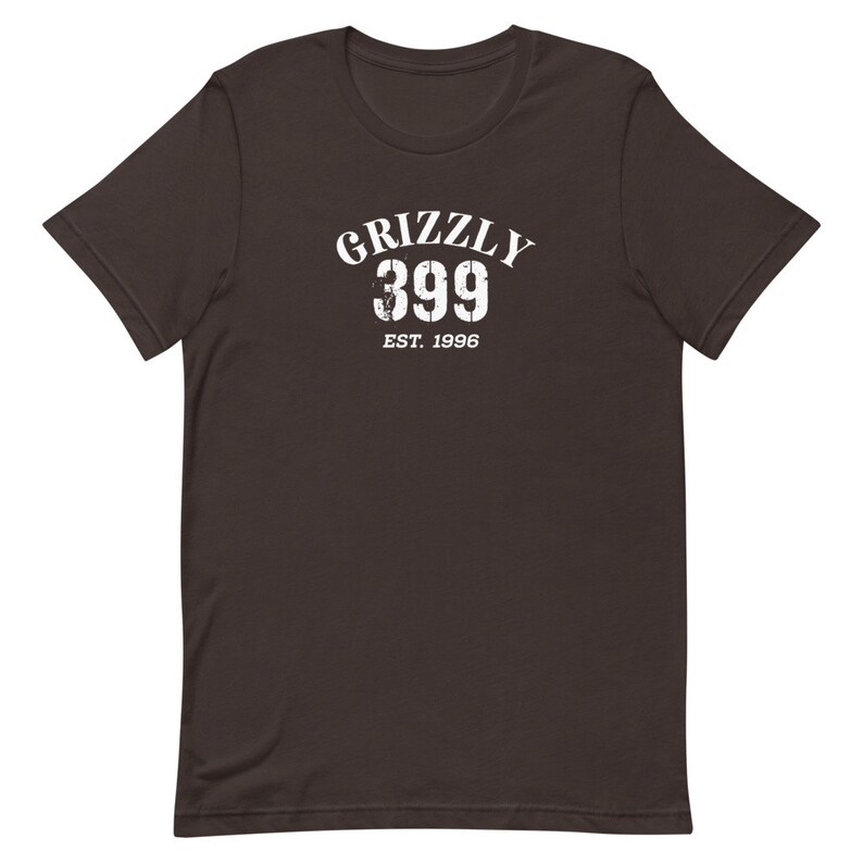 May include: A dark brown t-shirt with a white graphic print that says "Grizzly 399 Est. 1996".