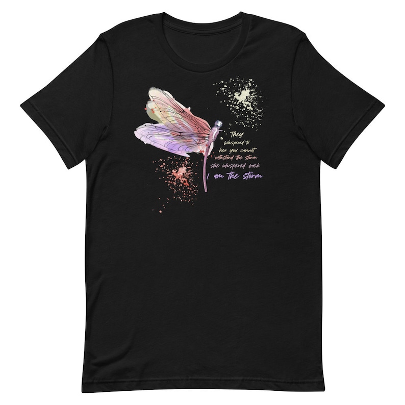 May include: Black t-shirt with a watercolor dragonfly design and the text "They whispered to her you cannot withstand the storm she whispered back I am the storm".