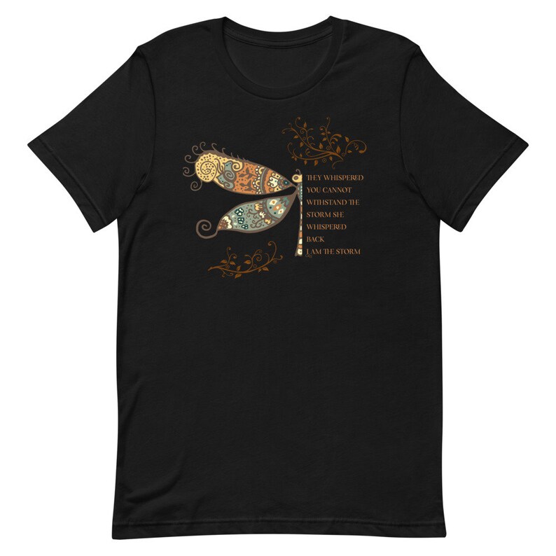 May include: Black t-shirt with a colorful dragonfly graphic and the text "They whispered you cannot withstand the storm she whispered back I am the storm".