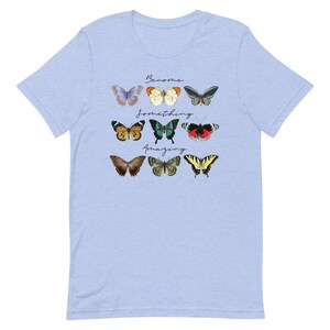 May include: Light blue t-shirt with a design of colorful butterflies and the text "Become something amazing".