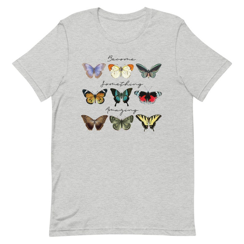 May include: A heather grey t-shirt with a design of colorful butterflies and the text "Become something amazing".