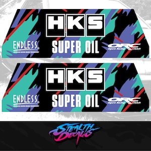 Puede incluir: Dos pegatinas en blanco y negro con un fondo abstracto de colores. Las pegatinas muestran el texto "HKS SUPER OIL" y "ENDLESS ADVANCED RACING BRAKE TECHNOLOGY" con el logotipo "ORC Ogura Racing Clutch".