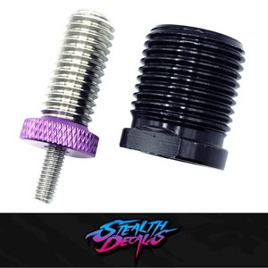 Puede incluir: Primer plano de dos piezas metálicas, una con una tapa roscada morada y la otra con una tapa roscada negra. Ambas piezas se utilizan para personalizar coches RC.