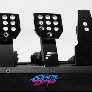 May include: Black racing pedals with a textured surface and multiple holes. The pedals are mounted on a black metal frame. The text "Stealth Decals" is visible in the lower right corner.