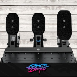 May include: Black racing pedals with textured foot pads. The set includes three pedals mounted on a black base. The logo "G" is visible on the base. The text "Stealth Decals" is at the bottom.