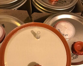 May include: Close-up of several silver jar lids with red rubber seals and a white label that reads "Craft Seals - Quality - Timeless".