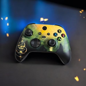 May include: A wireless video game controller featuring a custom graphic design with a gradient of yellow and green colors. The faceplate displays a glowing, intricate circular symbol on the left side, alongside standard black joysticks and buttons.
