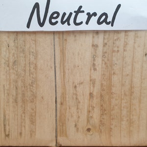 May include: A close-up of a light brown wood surface with a vertical grain pattern. The wood has a natural, unpainted finish. The word "Neutral" is written in black on a white label above the wood.