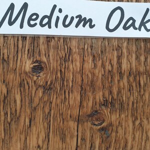 May include: Close-up of a wood grain texture with a medium oak finish. The wood has a natural brown color with knots and grain patterns.
