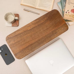 a wooden tray, a laptop, a cell phone, and some books arranged on a table.