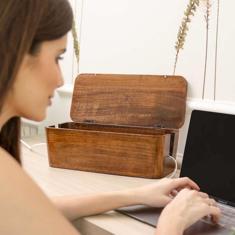 A woman is sitting at a desk, typing on a laptop computer.