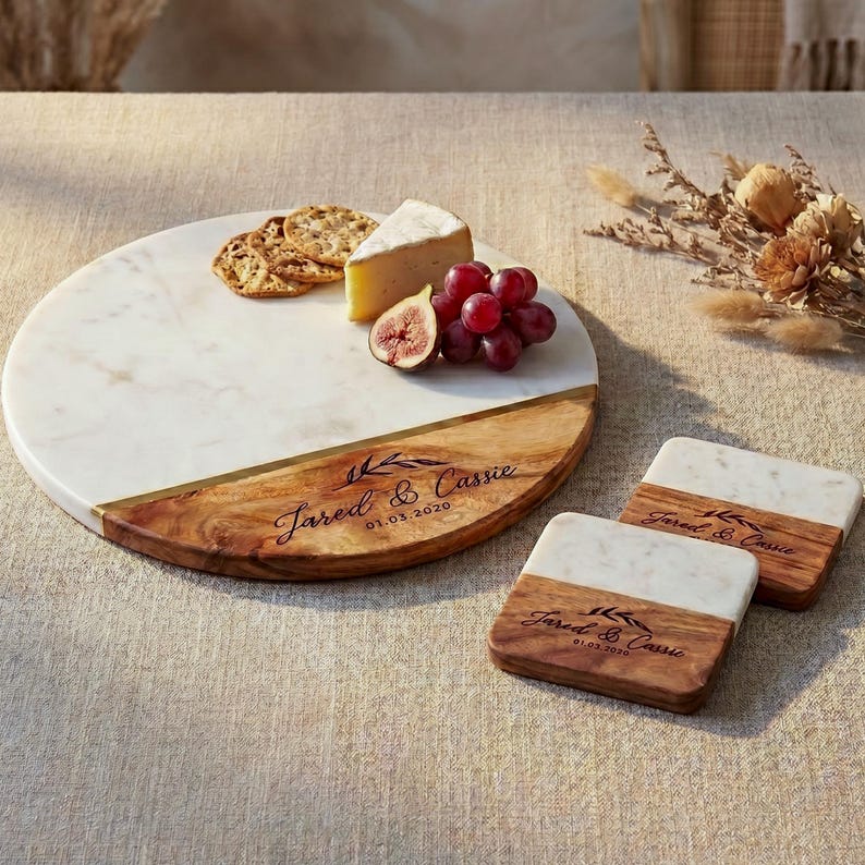 a round marble serving platter with a wooden rim, displaying a variety of food items such as grapes, cheese, and crackers. The platter is placed on a table, and there are coasters underneath it.