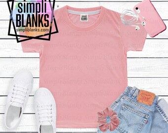 Könnte beinhalten: Ein hellrosa T-Shirt mit dem Text "simpli BLANKS simpliblanks.com" in einem schwarzen Rahmen. Das Shirt wird mit weißen Turnschuhen, hellblauen Jeans, einem rosa Scrunchie und einem rosa Telefon mit weißen Ohrhörern kombiniert.
