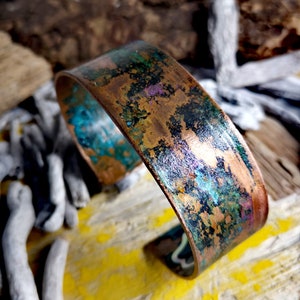 May include: A copper bracelet with a distressed, oxidized finish. The bracelet has a turquoise, green, and purple patina.