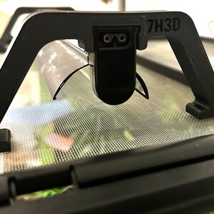 Puede incluir: Un accesorio de l&aacute;mpara de pl&aacute;stico negro con una pantalla de metal y un cable de alimentaci&oacute;n. El accesorio est&aacute; etiquetado como "7H3D".