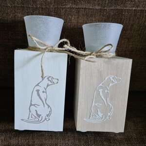 Könnte beinhalten: Zwei Kerzenhalter aus Holz mit einem Hundesilhouetten-Design. Die Kerzenhalter sind weiß und aus Naturholz mit mattierten Glaskerzenbechern.