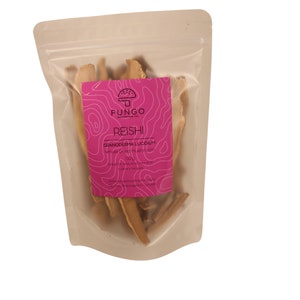 Puede incluir: Una bolsa de plástico transparente con una etiqueta rosa que dice "FUNGO" y "REISHI" con un gráfico de hongo. La etiqueta también dice "GANODERMA LUCIDUM" y "Hongo seco del vendedor" con un fondo blanco. La bolsa contiene hongos secos.