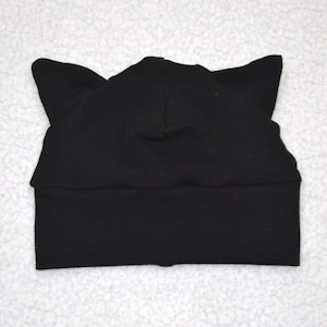 May include: Black knit beanie with cat ears. The beanie is made of a soft, stretchy fabric.