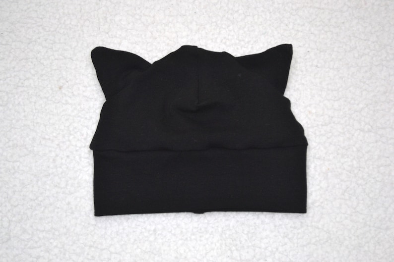 May include: Black knit beanie with cat ears. The beanie is made of a soft, stretchy fabric.