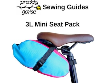 May include: A blue and pink 3L Mini Seat Pack attached to a bicycle seat. The bag is secured with a black strap. The text "prickly gorse Sewing Guides" and "3L Mini Seat Pack" are visible in the image.