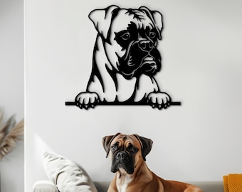 Könnte beinhalten: Schwarze Wandkunst aus Metall mit einem Boxer, der über einen Sims schaut. Der Hund blickt nach rechts mit einem ernsten Ausdruck. Die Kunst ist an einer weißen Wand über einem hellgrauen Sofa mit einem braunen Hund darauf montiert.