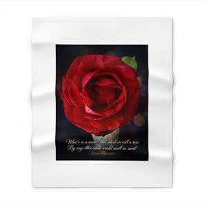 May include: A white fleece blanket featuring a central rectangular print of a deep red rose against a dark background. Below the rose, the text reads: What's in a name? that which we call a rose By any other name would smell as sweet - William Shakespeare.