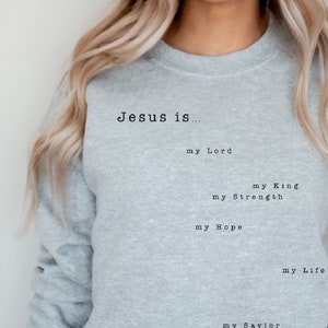 May include: A gray sweatshirt with the text "Jesus is... my Lord, my King, my Strength, my Hope, my Life, my Savior, my God" printed on the front.