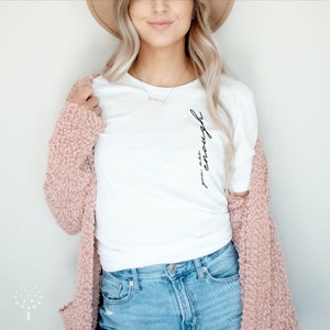 May include: White t-shirt with the text "you are enough" written vertically on the side.