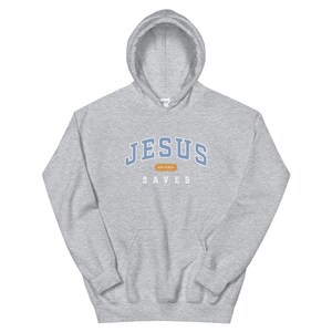 May include: A gray hooded sweatshirt with the text "JESUS SAVES" in blue and white lettering. The text "ACTS 16:30-31" is in a small brown rectangle.