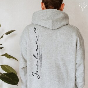 May include: Gray hooded sweatshirt with the text "Joshua 1:9" and the quote "Do not be afraid; do not be discouraged, for the Lord your God will be with you wherever you go. Have I not commanded you? Be strong and courageous." printed on the back.