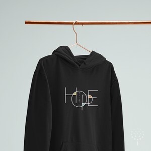 May include: Black hoodie featuring a white graphic of the word "HOPE" within a geometric circle design with colourful accents.