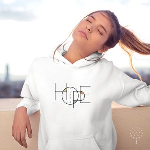 May include: White hoodie featuring a graphic design of the word "HOPE" in black and white with a circle in the centre of the word. The circle is filled with various colours, including beige, light blue, and yellow.
