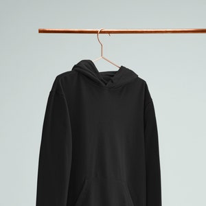 May include: A black hooded sweatshirt hanging on a copper hanger against a light blue background.