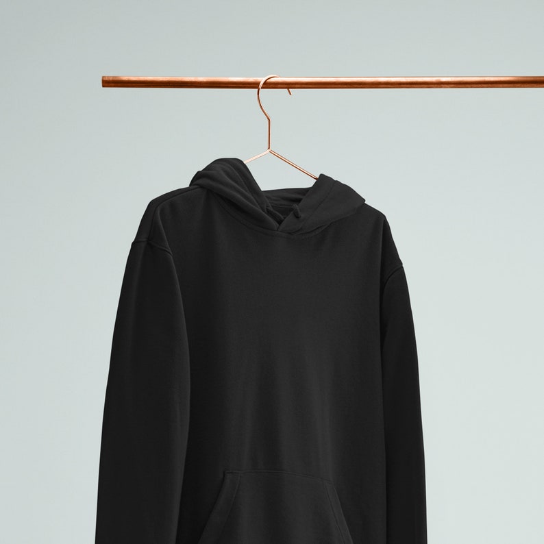 May include: A black hooded sweatshirt hanging on a copper hanger against a light blue background.