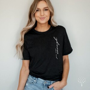 May include: A black t-shirt with the text "you are enough" written vertically on the left side of the shirt.