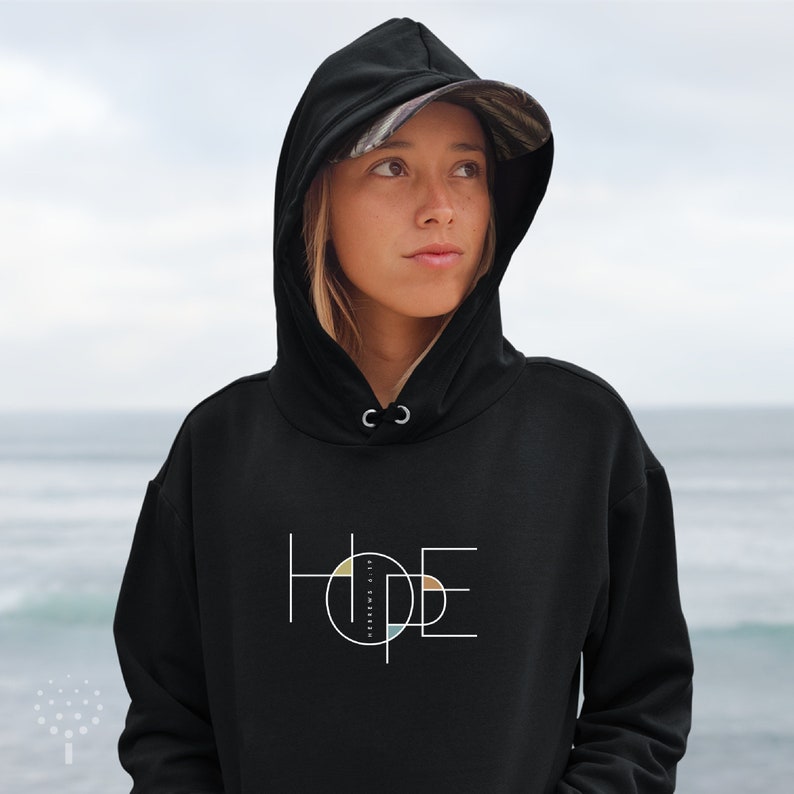 May include: Black hooded sweatshirt with a graphic design of the word "HOPE" in white with a circle containing a geometric pattern of yellow, orange, and blue in the centre of the word.