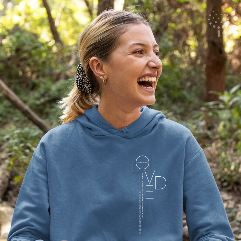 May include: A light blue hoodie with a white graphic that says "LOVED" with the word "ROMANS 5:8" in a circle above the "O".