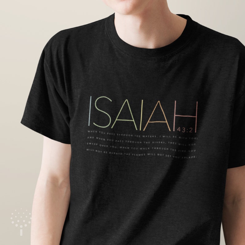 May include: Black t-shirt with the word "ISAIAH" in rainbow colors and the Bible verse "When you pass through the waters, I will be with you! And when you pass through the rivers, they will not sweep over you. When you walk through the fire, you will not be burned; the flames will not set you ablaze." printed in white below.