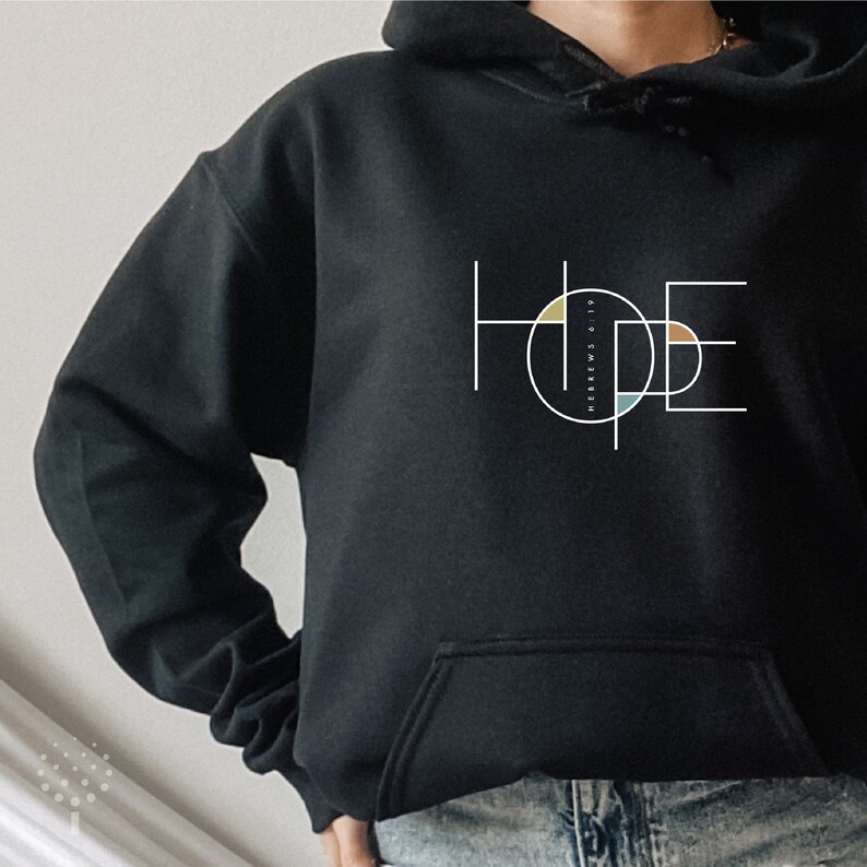 May include: Black hoodie with a white graphic of the word "HOPE" in a geometric design with colourful circles. The text "HEBREWS 10:23" is inside one of the circles.