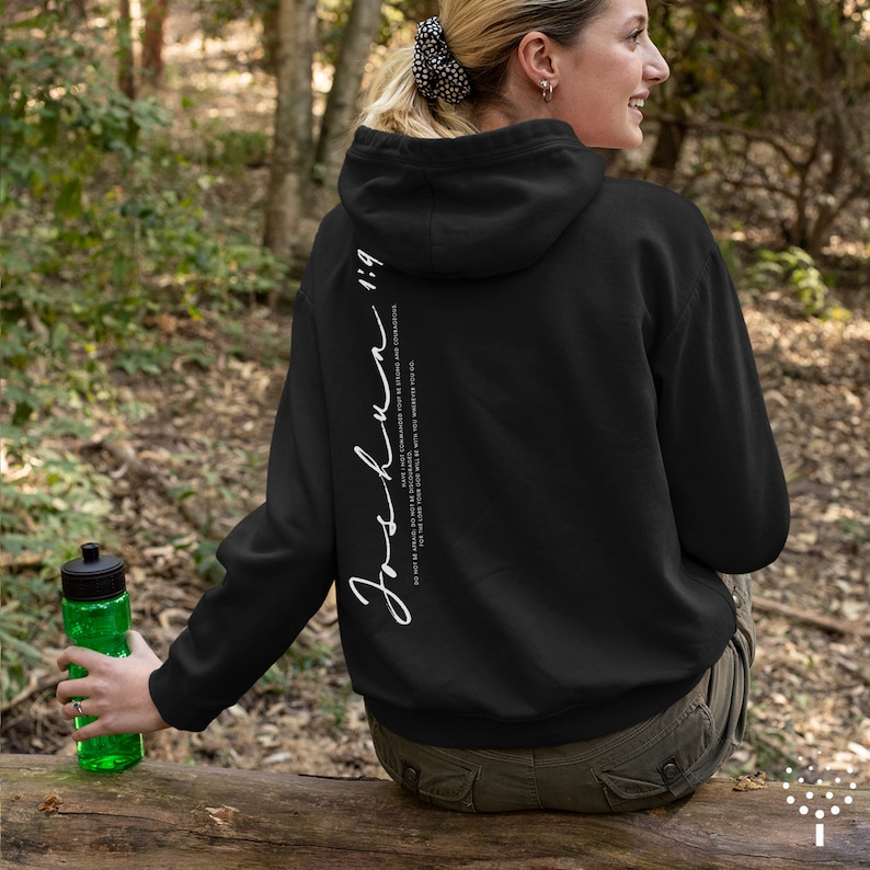 May include: Black hooded sweatshirt with white text on the back that reads "Joshua 1:9" and the quote "For I have commanded you to be strong and courageous. Do not be afraid; do not be discouraged, for the Lord your God will be with you wherever you go."