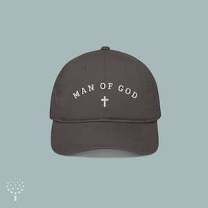 May include: A dark gray baseball cap with the text "MAN OF GOD" embroidered in white with a white cross in the center.